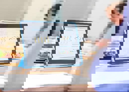 Man with tablet with graphs on table